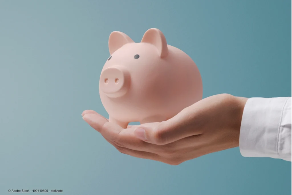 Ein rosa Sparschwein auf einer Hand symbolisiert bewusstes Sparen und finanzielle Kontrolle, um lifestyle inflation vermeiden zu können.