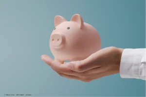 Ein rosa Sparschwein auf einer Hand symbolisiert bewusstes Sparen und finanzielle Kontrolle, um lifestyle inflation vermeiden zu können.